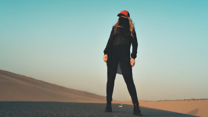 Photo by Adryan RA woman in black jacket and pants standing on gray sand during daytime