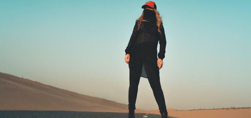 woman in black jacket and pants standing on gray sand during daytime