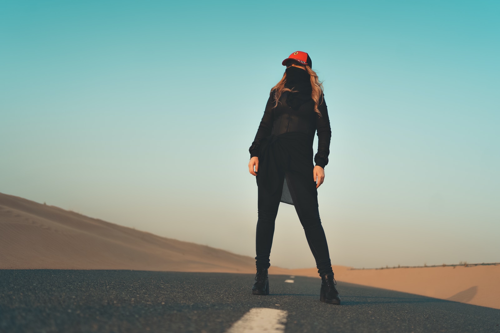 woman in black jacket and pants standing on gray sand during daytime